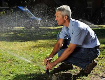 an irrigation contractor is doing a maintenance check on a sprinkler head